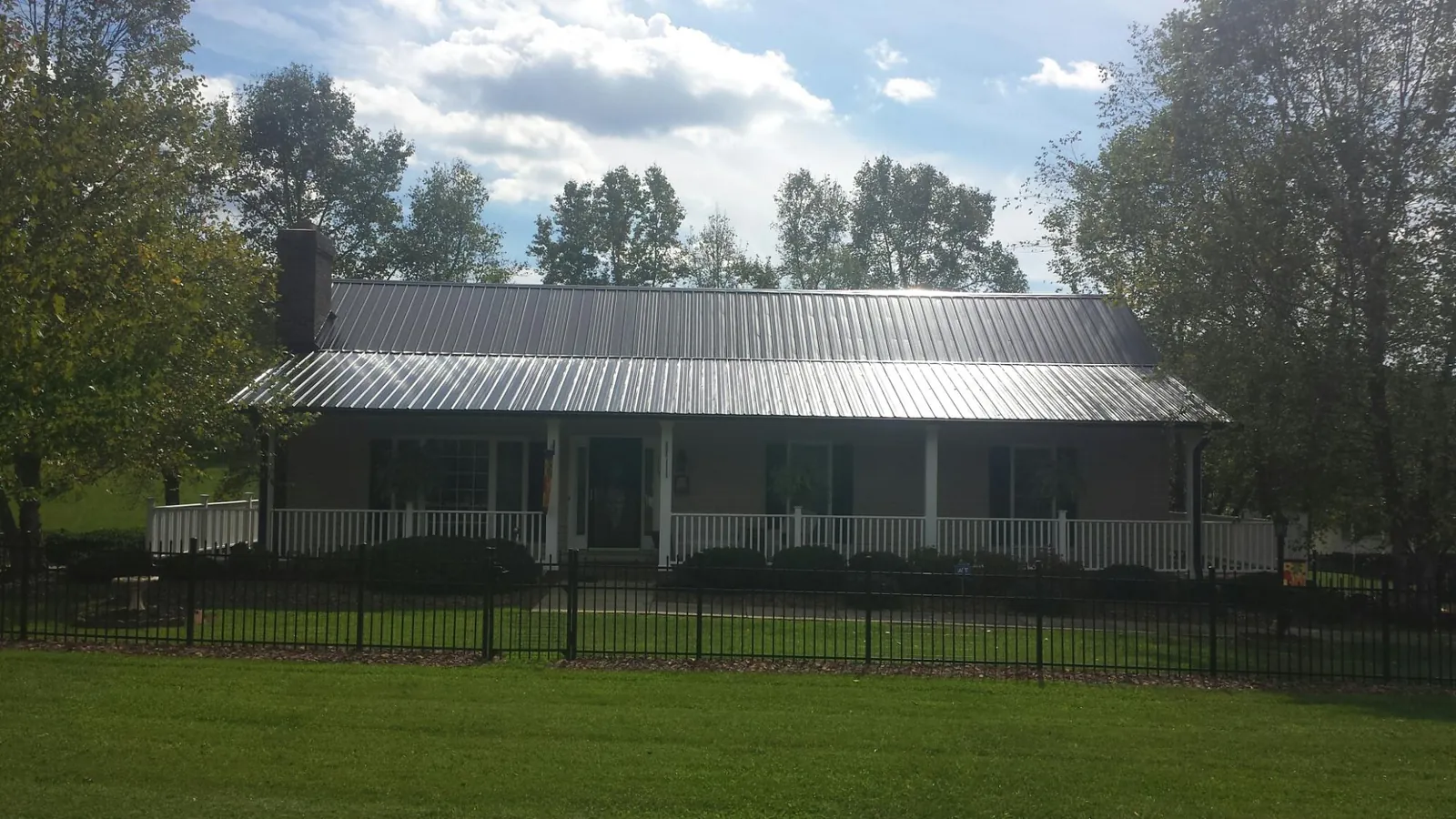 Gray metal roof on a brick ranch with a full width front porch — Gutter Guard Installation work by our crew in Hays
