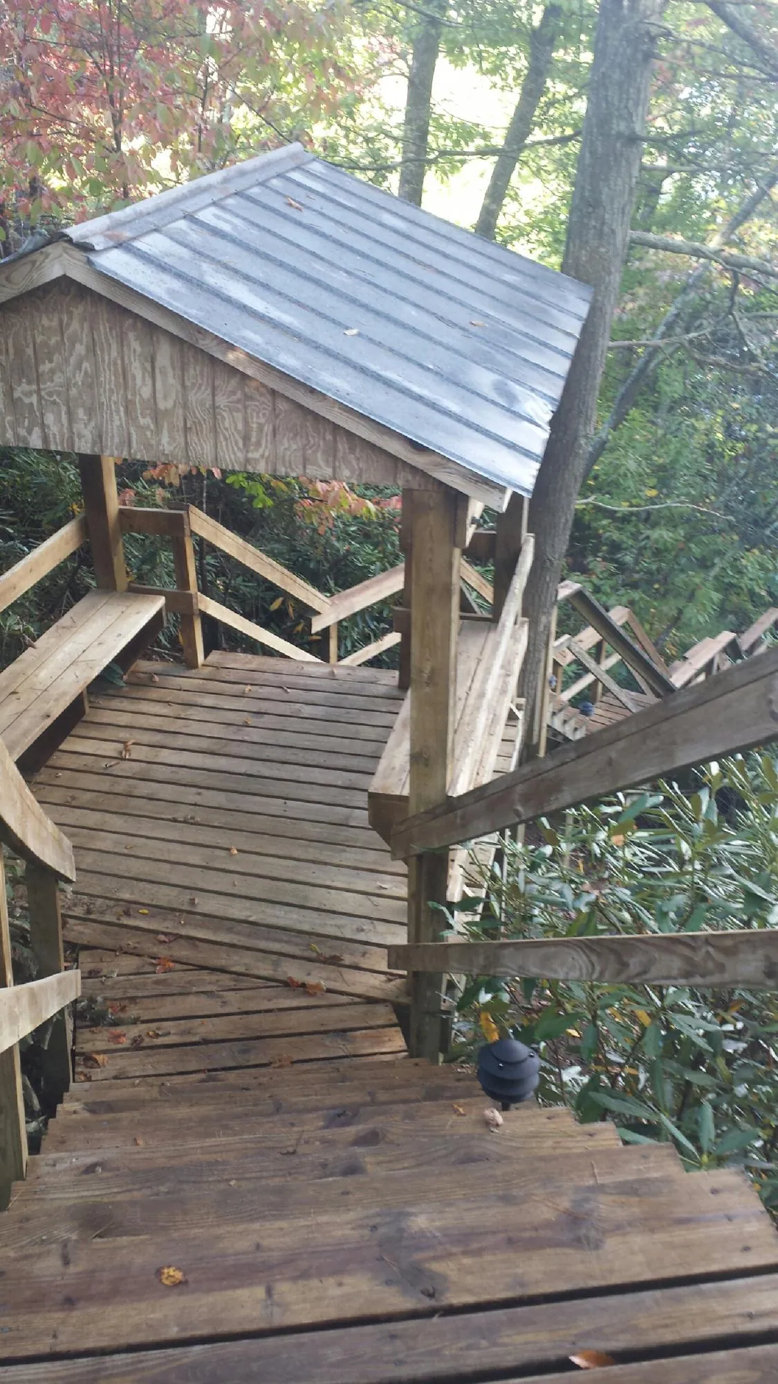 Metal roofed shelter over wooden steps on a wooded walkway — Skylight Repair & Installation work by our crew in Hays