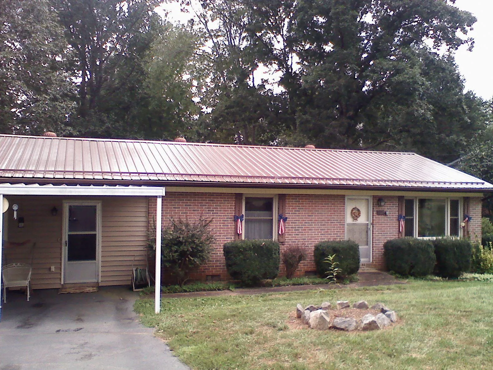 Bronze metal roof and carport on a brick ranch home — Roof Repair work by our crew in Hays